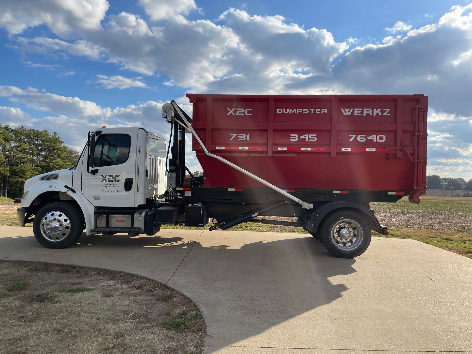 A red dumpster is being towed by a truck.