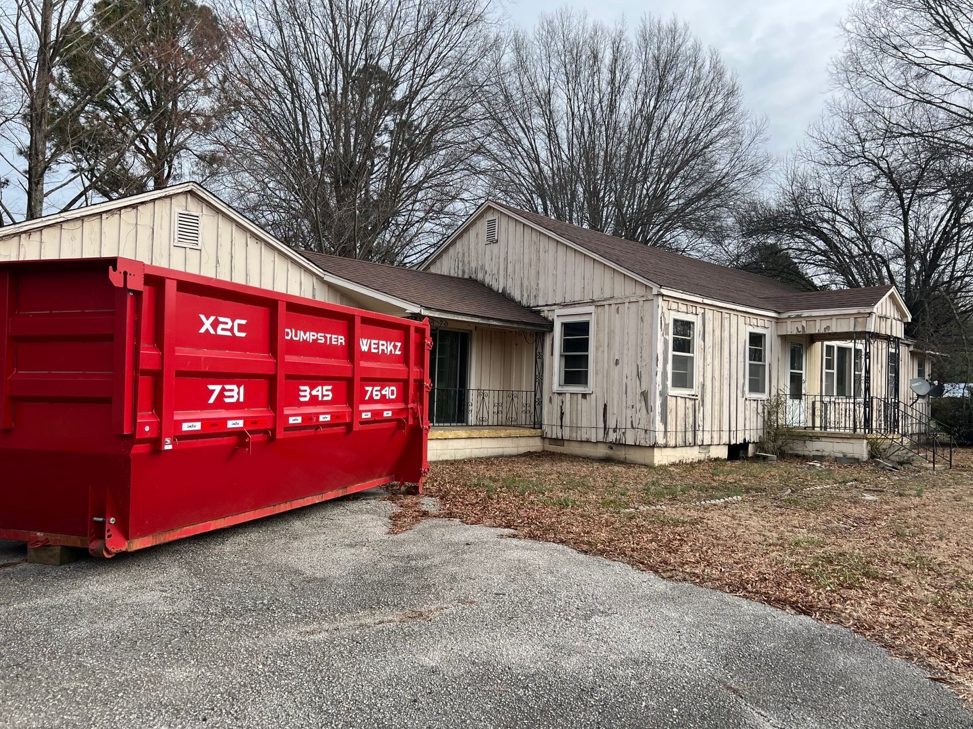 A red dumpster is parked in front of a house.