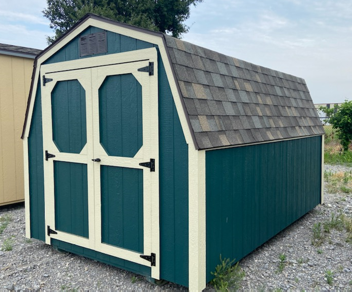 Green and cream shed with a barn-style roof and double doors, outdoors.