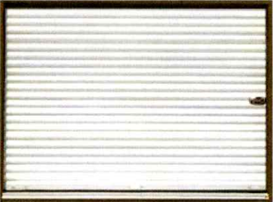 Roller shutter door, closed and silver-colored, with a small handle on the right.
