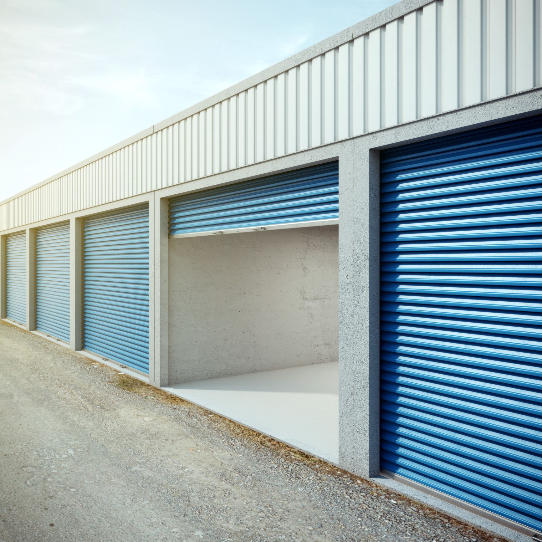 An empty storage unit with an open door surrounded by others