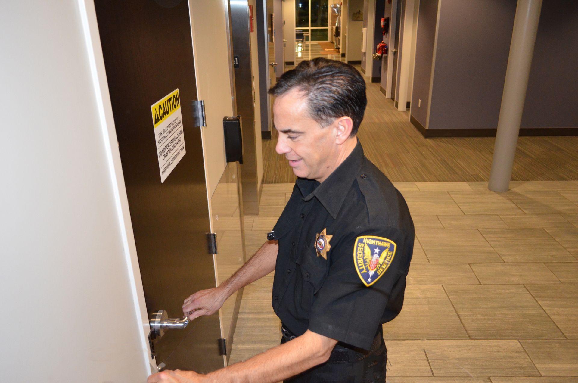 A person in uniform opening a door in a hallway.
