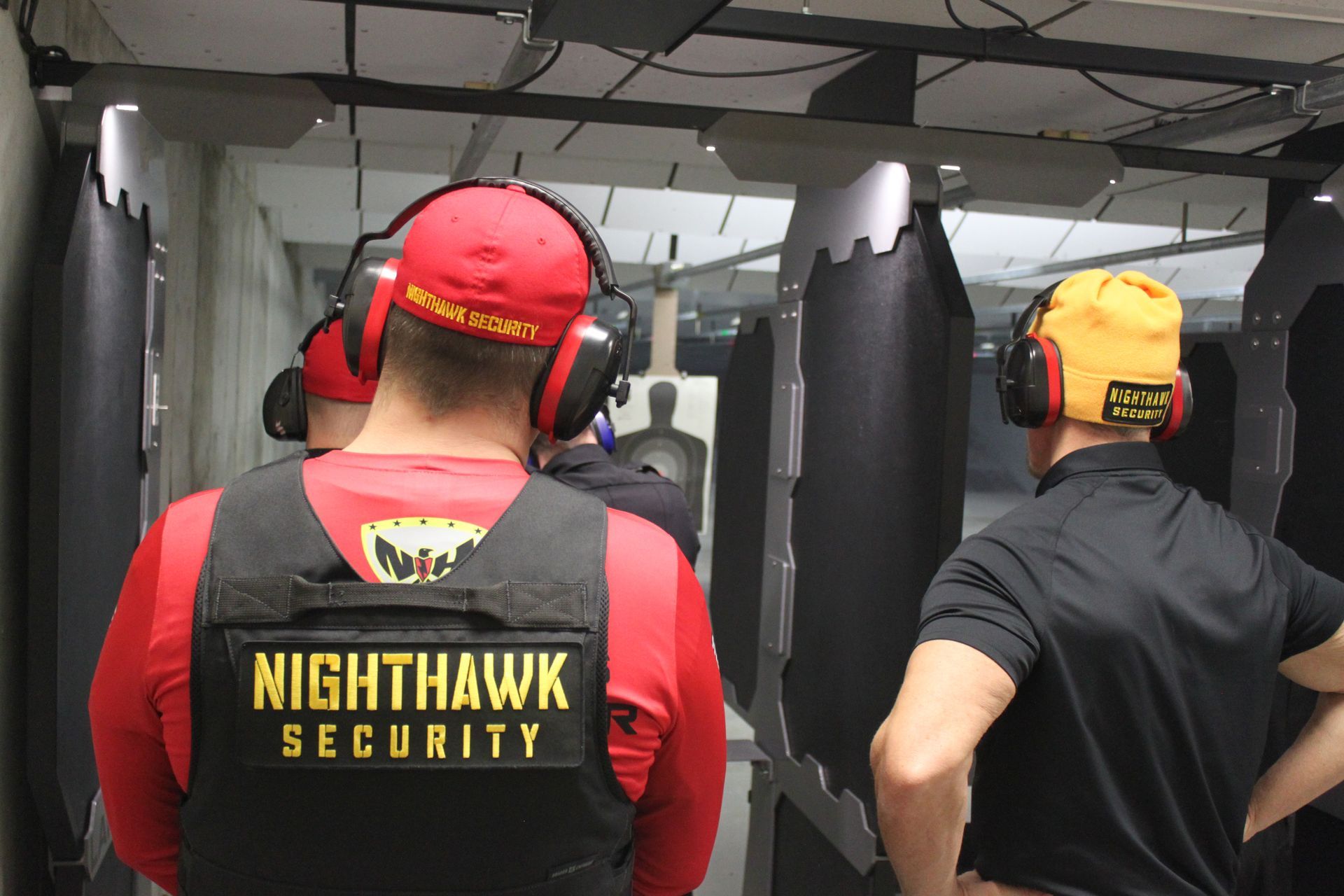 People at a shooting range wearing ear protection and safety vests. 