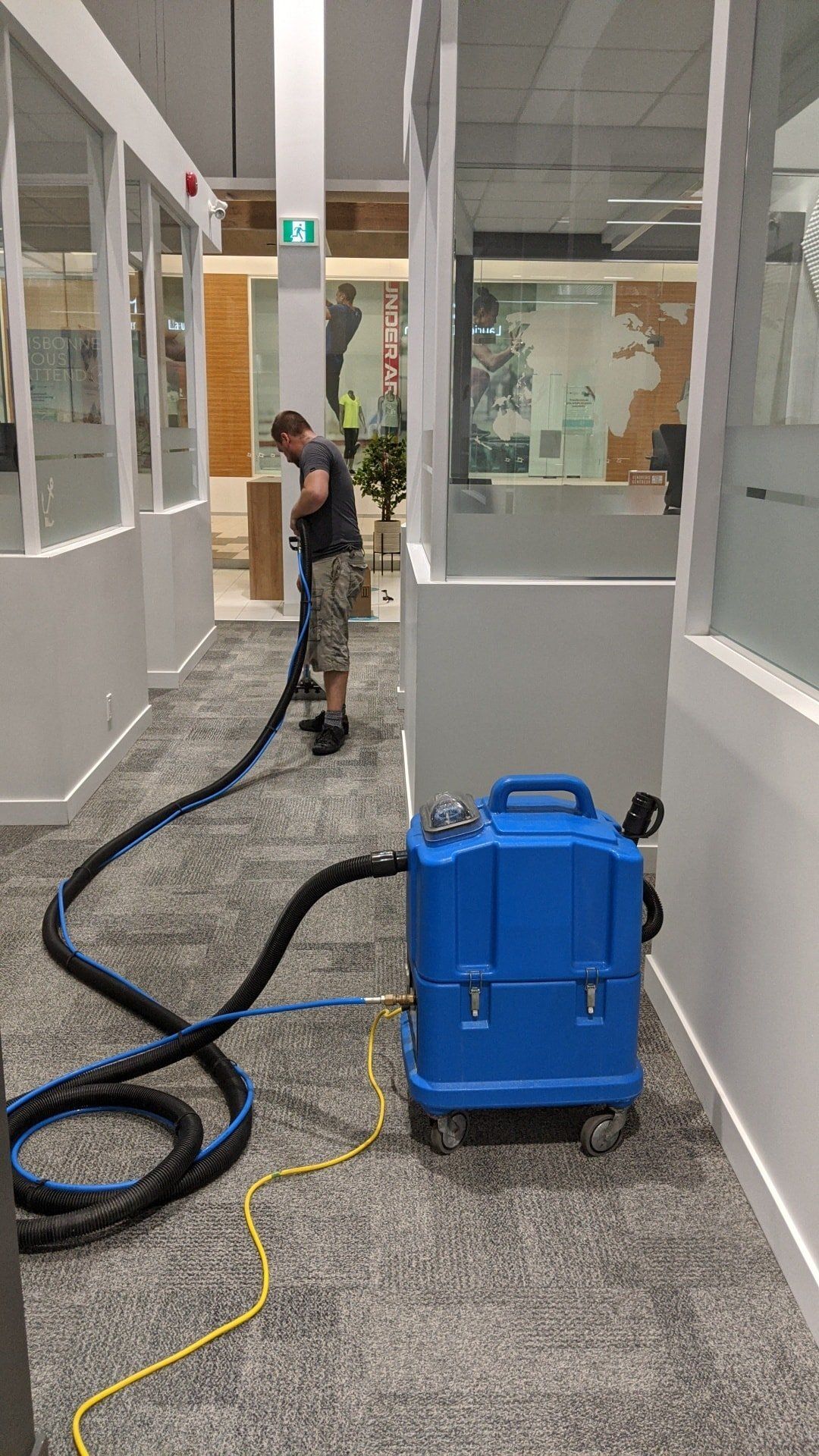 Un homme utilise un aspirateur pour nettoyer un tapis dans un bureau.