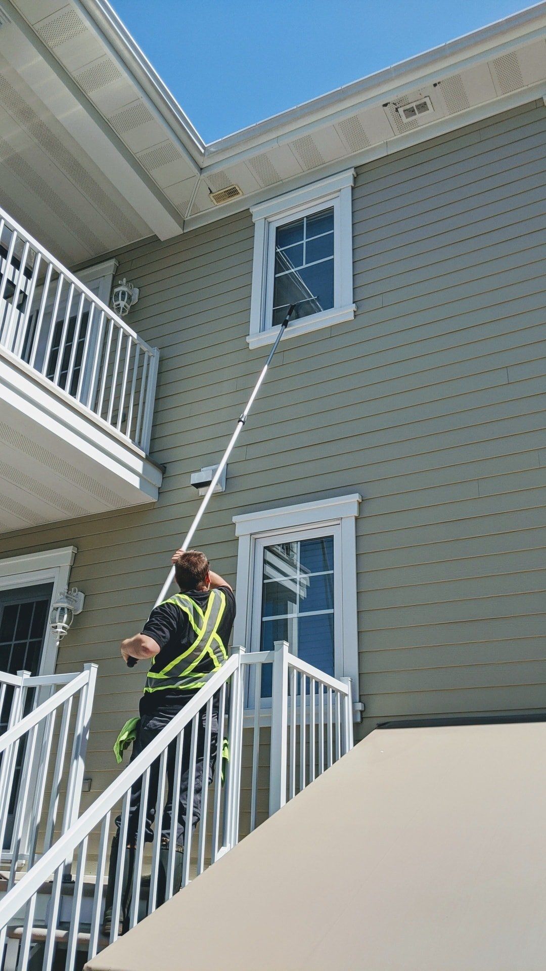Un homme nettoie une fenêtre sur le côté d'un bâtiment.