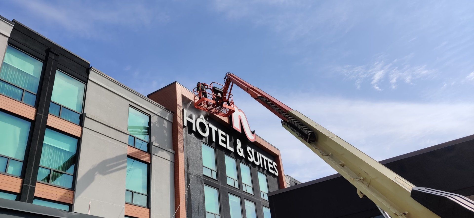 Une grue soulève un panneau sur le côté d'un bâtiment.