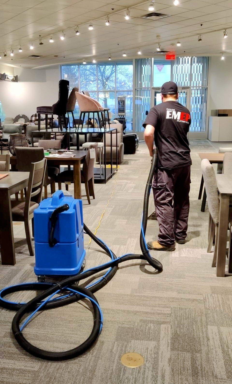 Un homme nettoie le sol d'un restaurant avec un aspirateur.
