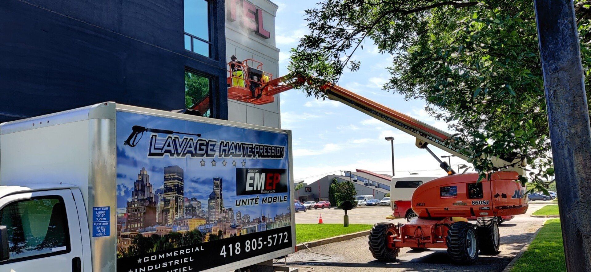 Un camion est garé devant un bâtiment avec une grue attachée dessus.