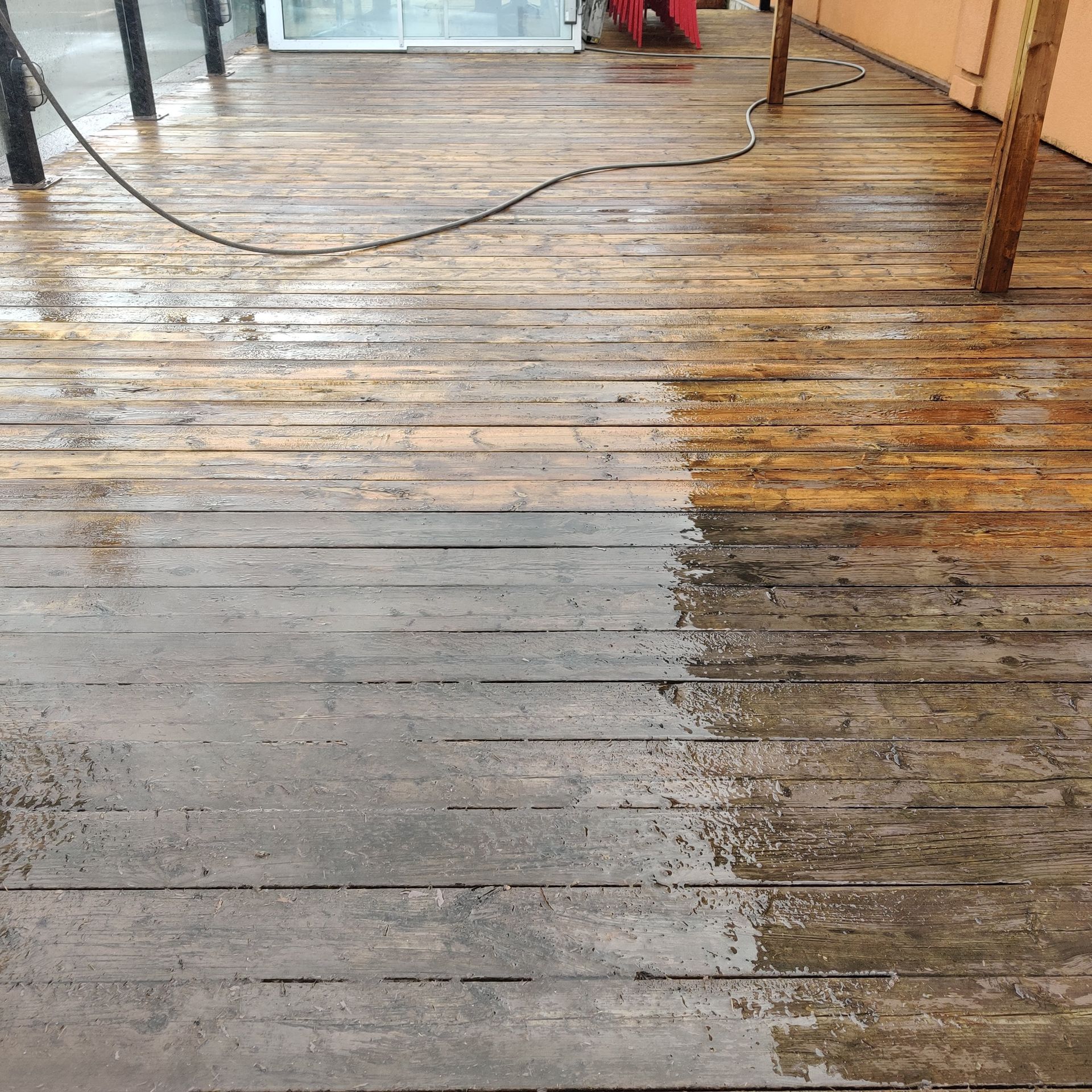 Une terrasse en bois est nettoyée avec un nettoyeur haute pression.