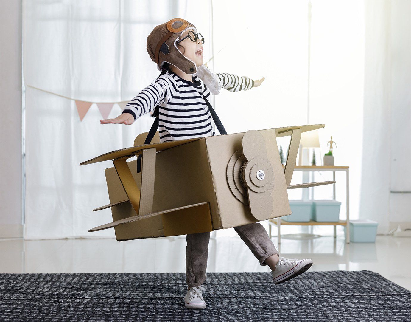 child playing with cardboard plane