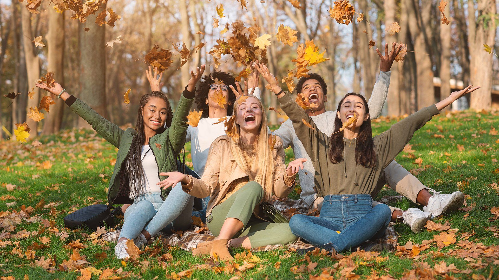 friends playing with leaves in the park
