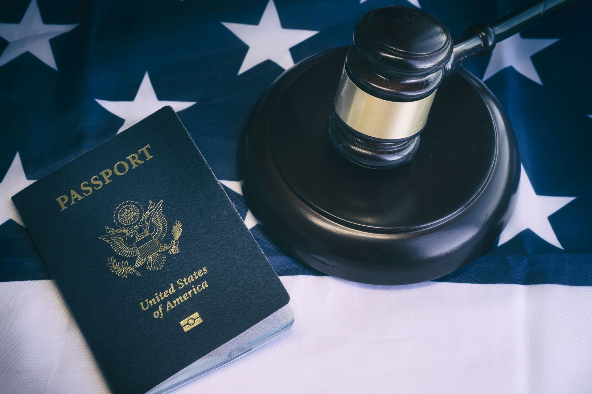 A passport is sitting on top of an american flag next to a judge 's gavel.