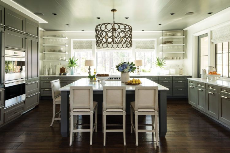 Bright modern kitchen with white island, dark wood floor, pendant light, and large windows