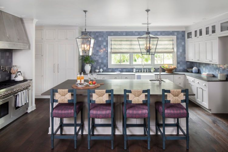 Bright modern kitchen with blue island, pendant lights, and barstools by a windowed sink