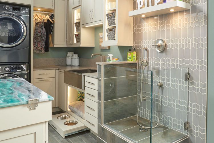 Laundry room with stacked washer and dryer, cabinetry, sink, and glass storage drawers.