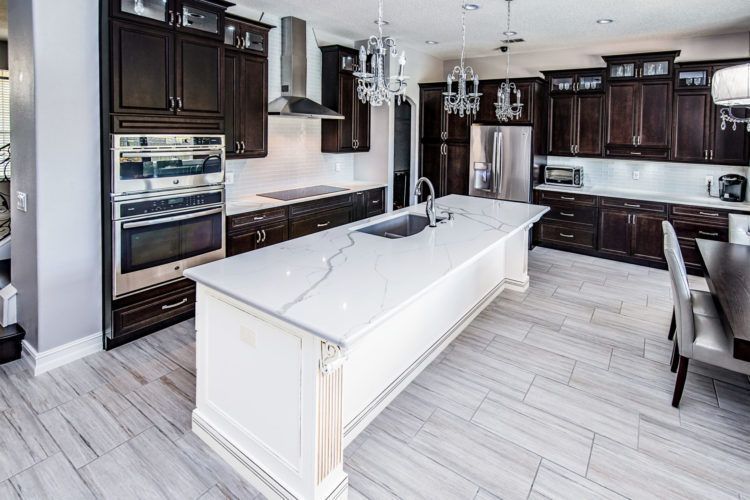 Modern kitchen with dark wood cabinets, white island, and light gray flooring