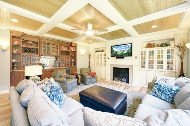Bright living room with white coffered ceiling, sectional sofa, fireplace, TV, and built-in shelves