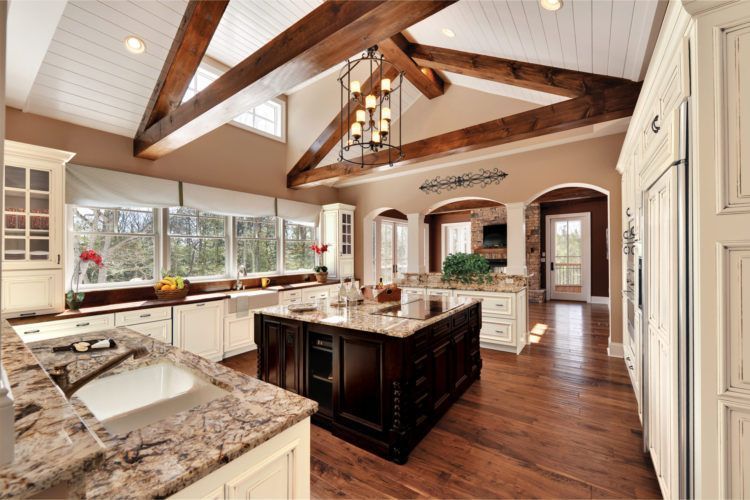 Bright open kitchen with wood beams, granite island, white cabinets, and hardwood floors