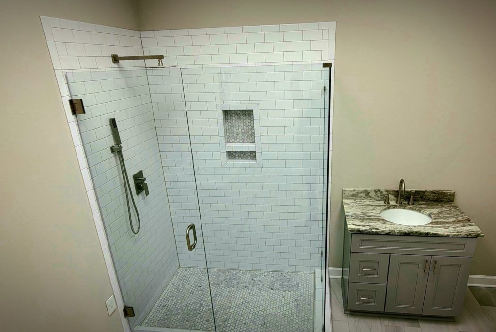 Small bathroom with tiled shower stall and a vanity sink on the right.