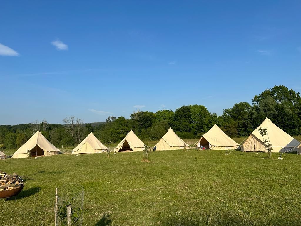 photo of a row of bell tents with trees and blue sky behind