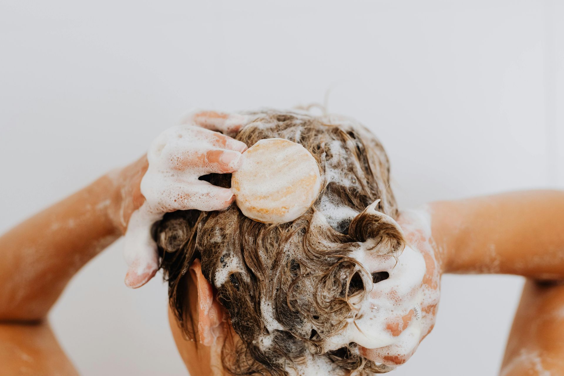photo of the back of a ladies head, she is washing her hair