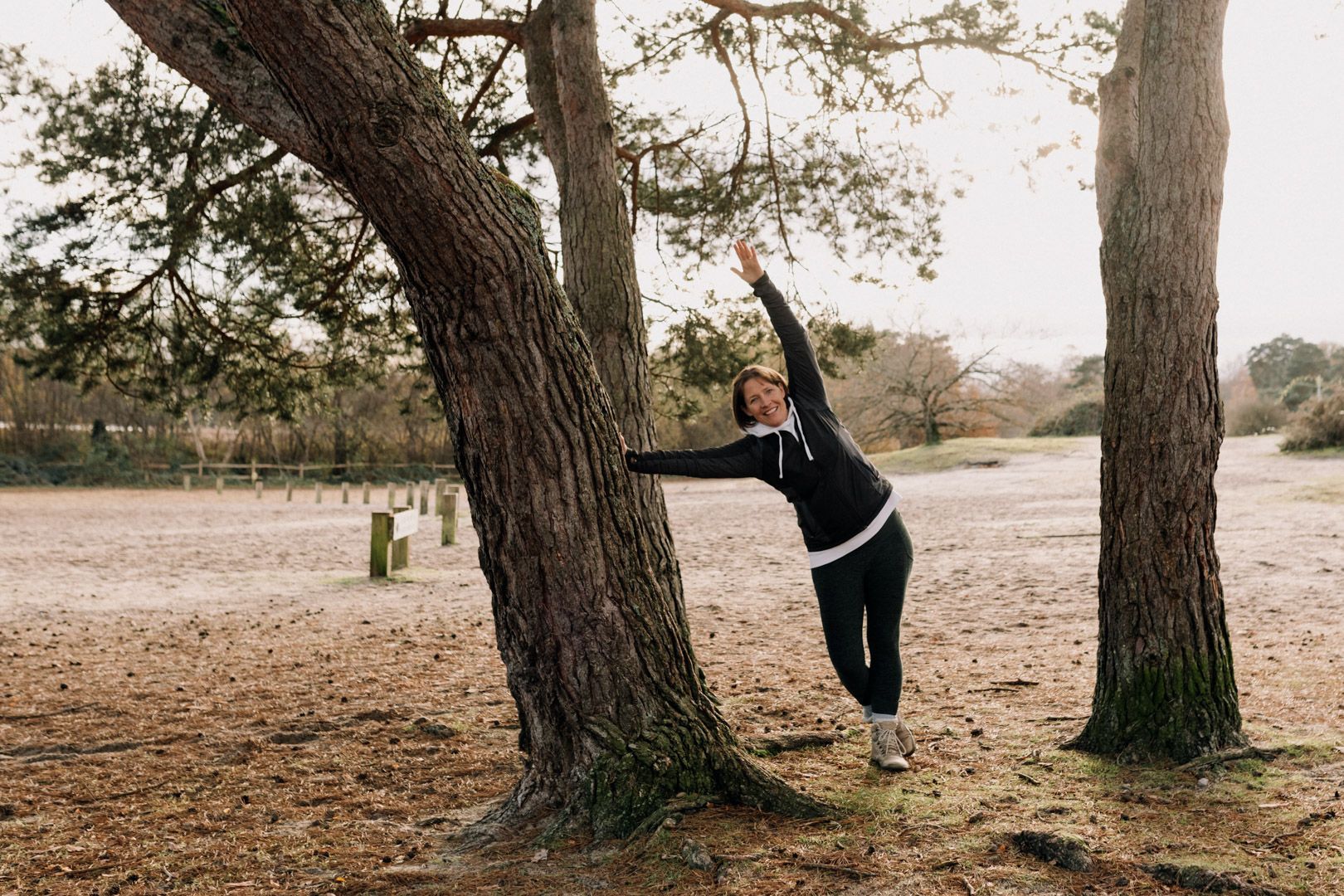 photo in the autumn with a person doing a side stretch against a tree