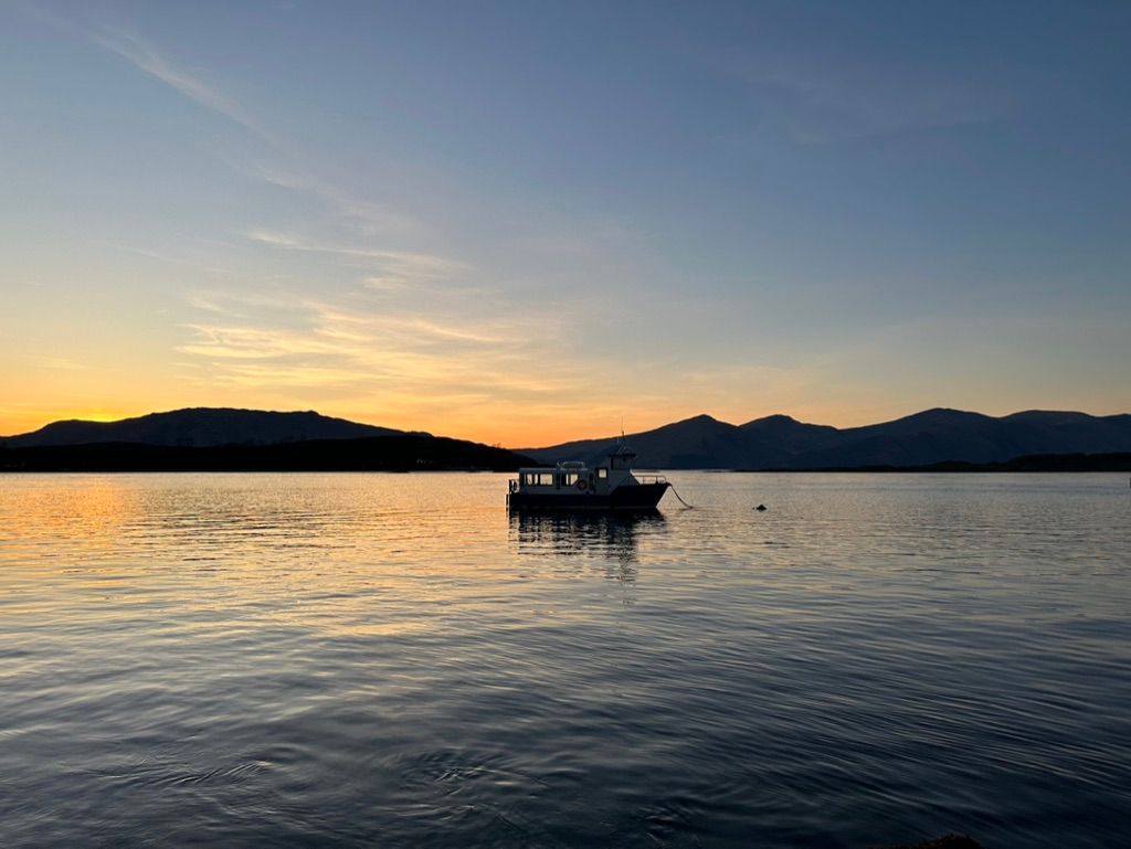 A photo of a sunset over water with a little boat in the foreground