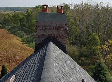 A brick chimney is being built on top of a roof.