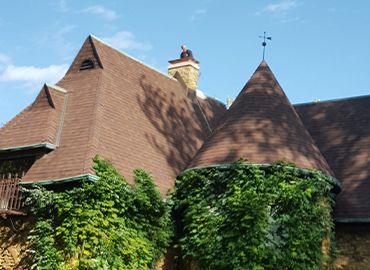 The roof of a house has a weather vane on top of it.