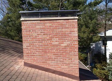 A chimney on the roof of a house with trees in the background