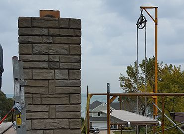A brick chimney is being built on top of a roof.