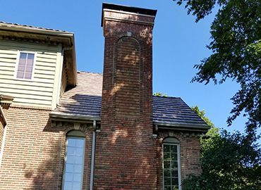 A brick house with a chimney on the side of it.