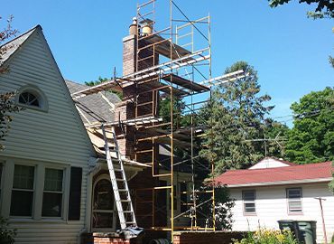 A chimney on the roof of a house with trees in the background