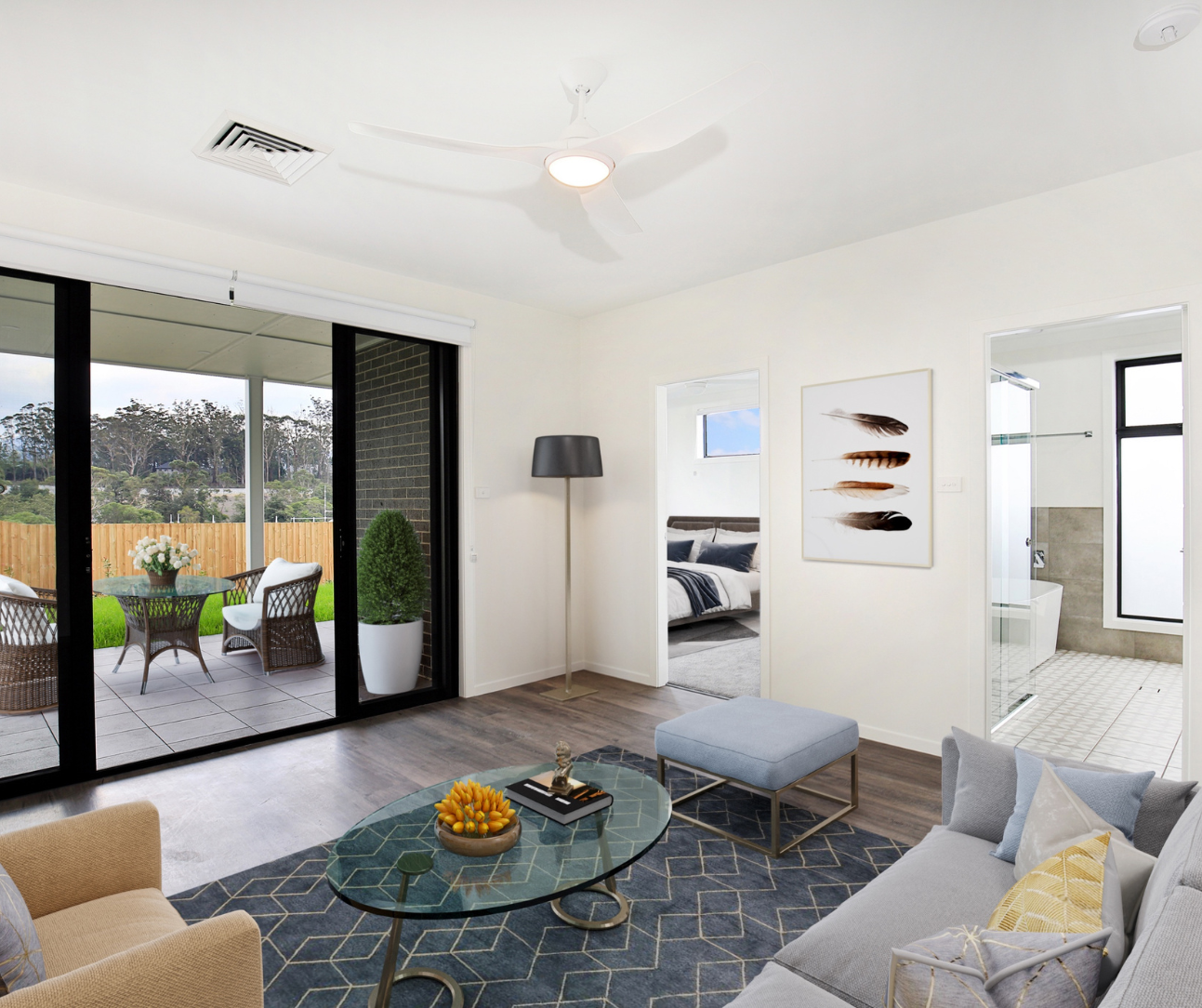 Bright modern living room with gray sofa, blue rug, and patio doors to a garden seating area