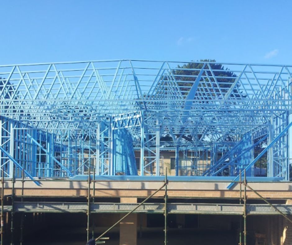 Building a steel frame house under construction with blue trusses.