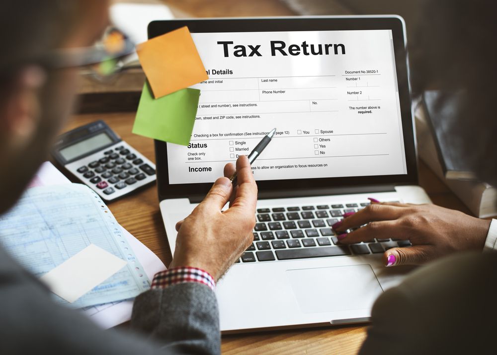 A Man Is Using a Laptop Computer to Fill out A Tax Return Form — Figures Right in Jerrabomberra, NSW