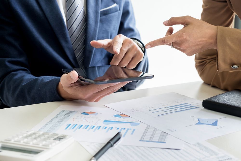 Two Men Are Sitting at A Table Looking at A Tablet — Figures Right in Jerrabomberra, NSW