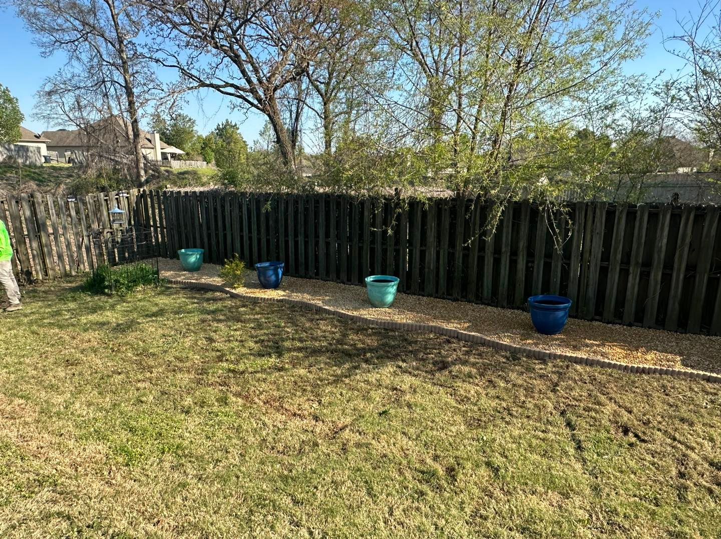 A backyard with a wooden fence and potted plants.