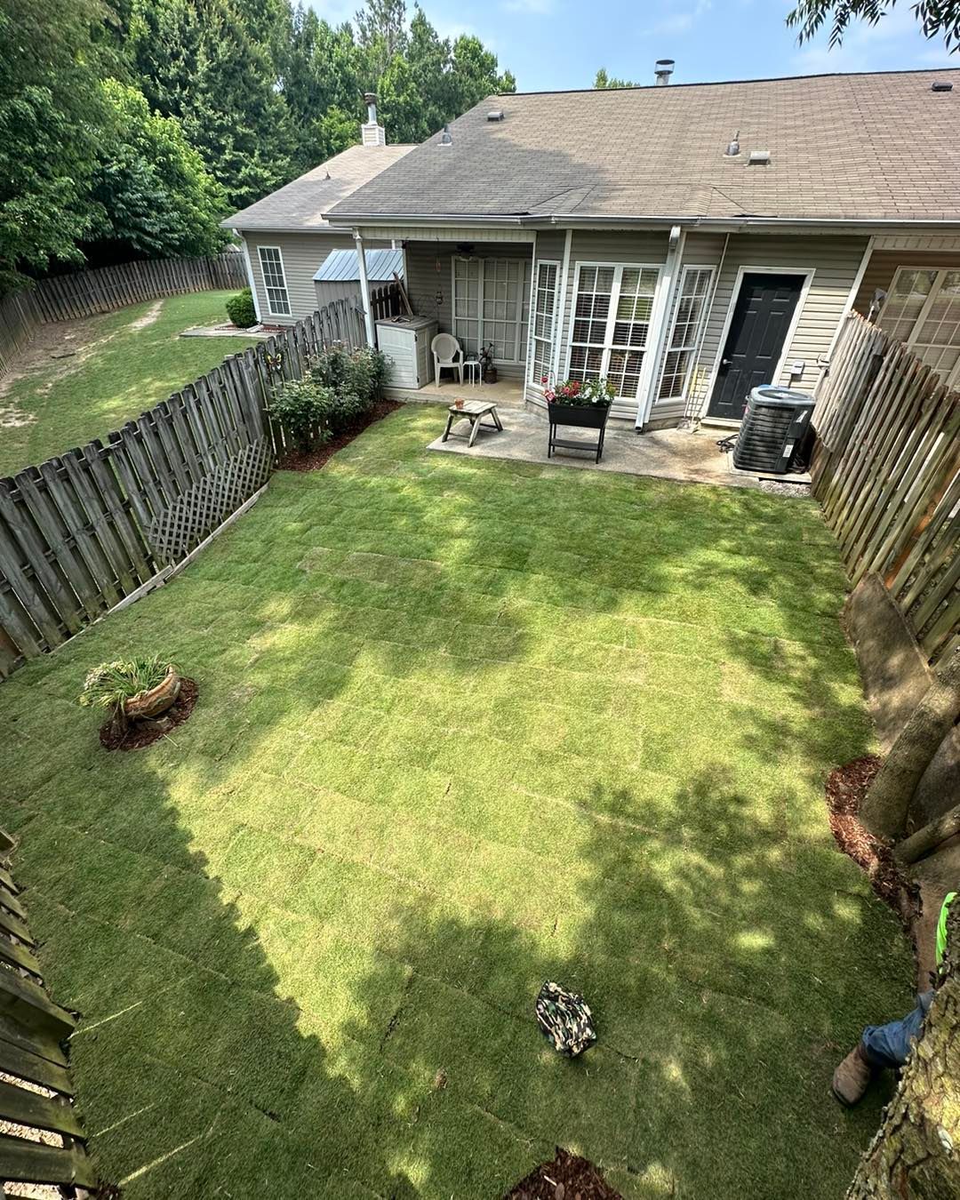 An aerial view of a backyard with a fence and a house in the background.