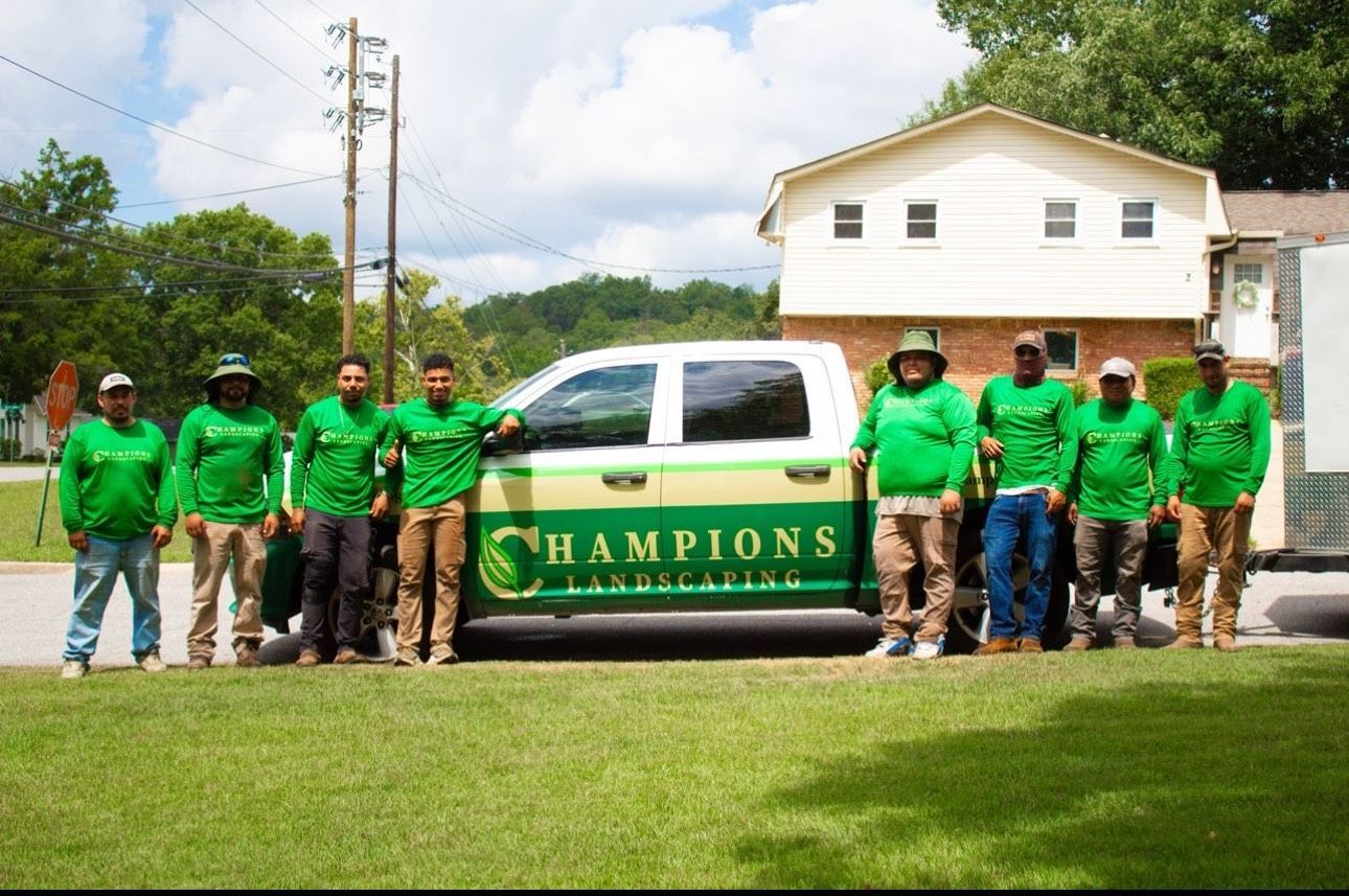 A group of men standing in front of a truck that says champions landscaping