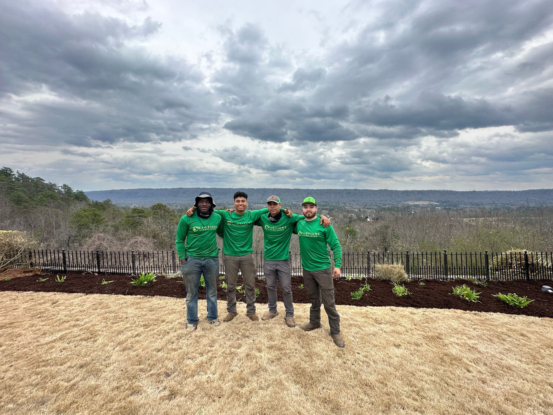 a group of men in green shirts are posing for a picture in a field .