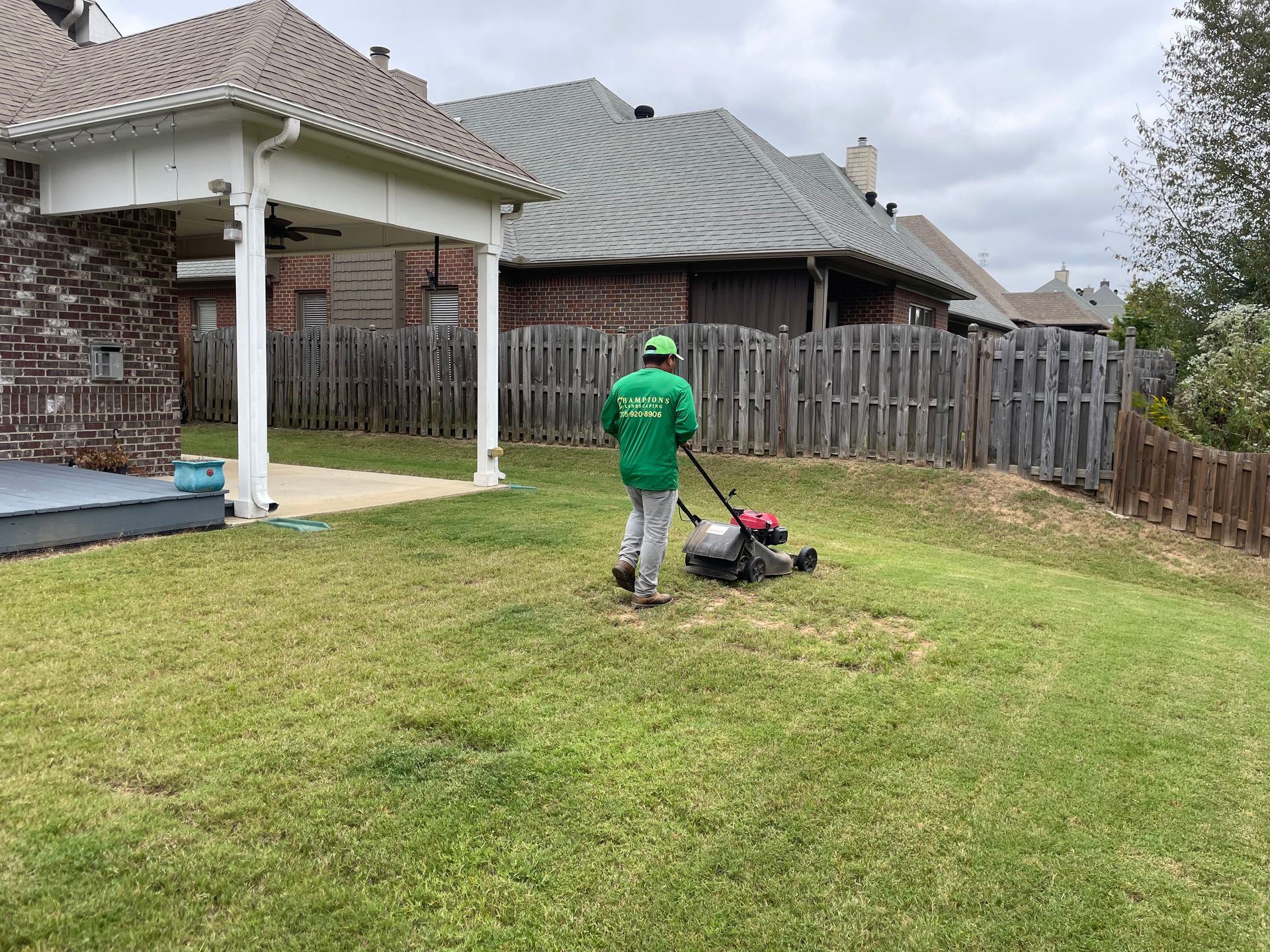 a man is mowing a lush green lawn in front of a house .