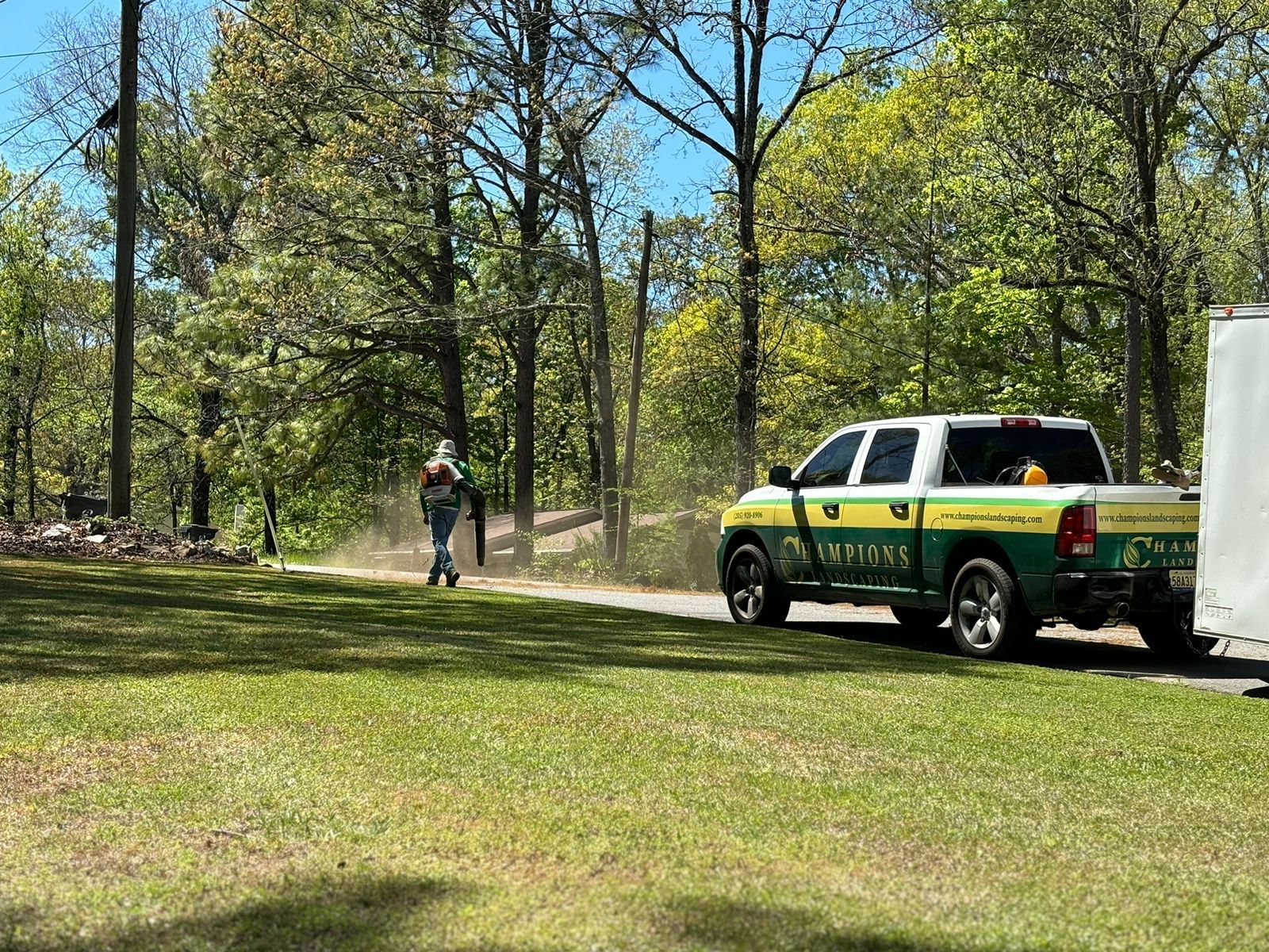 A green and yellow truck is parked on the side of the road next to a trailer.