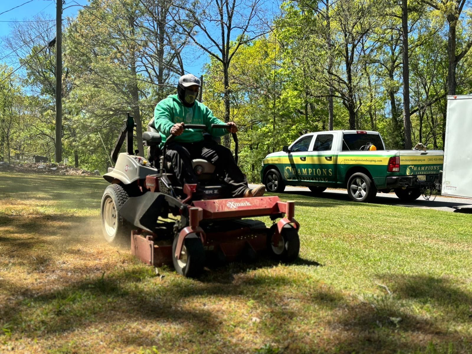 A man is riding a lawn mower on a lush green field.