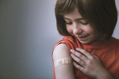 Girl smiles at bandage on arm.