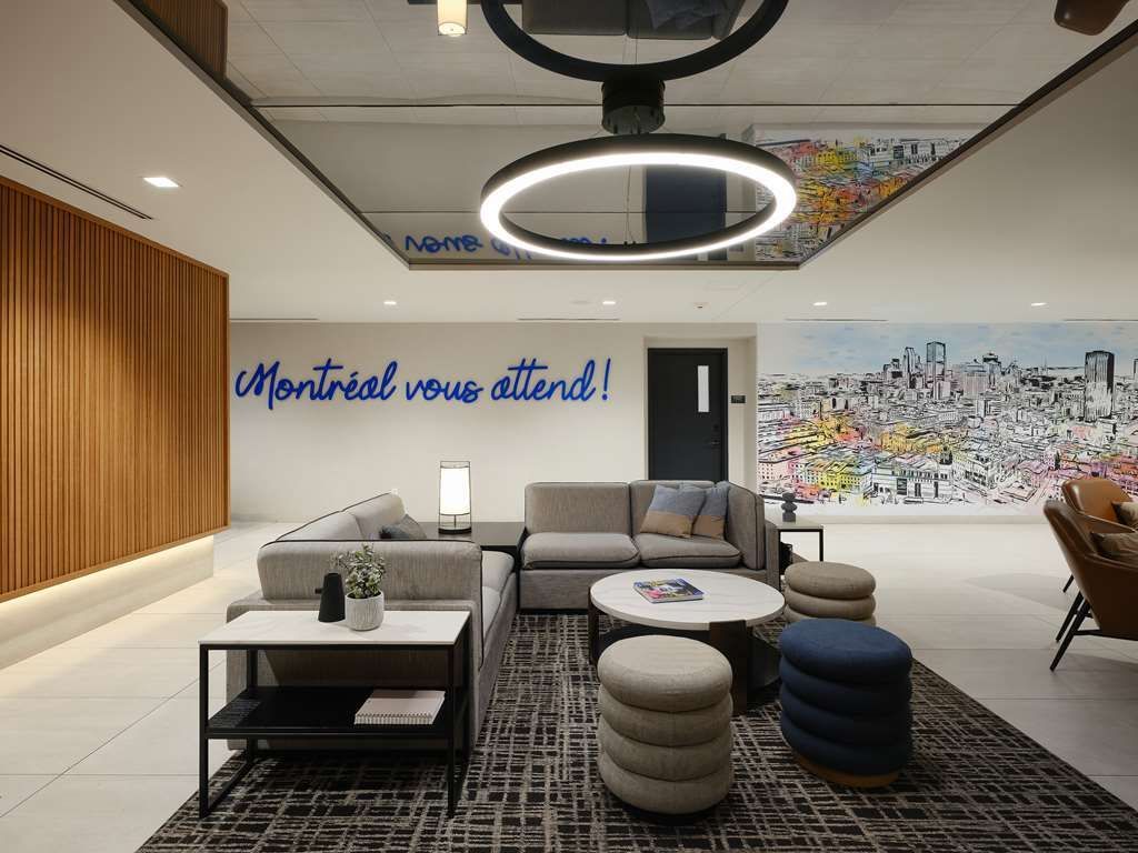 Un salon avec un canapé, une table, des chaises et une peinture murale sur le mur.