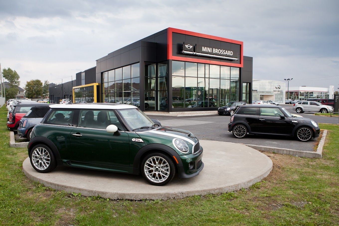 Une mini cooper verte est garée devant un concessionnaire automobile.