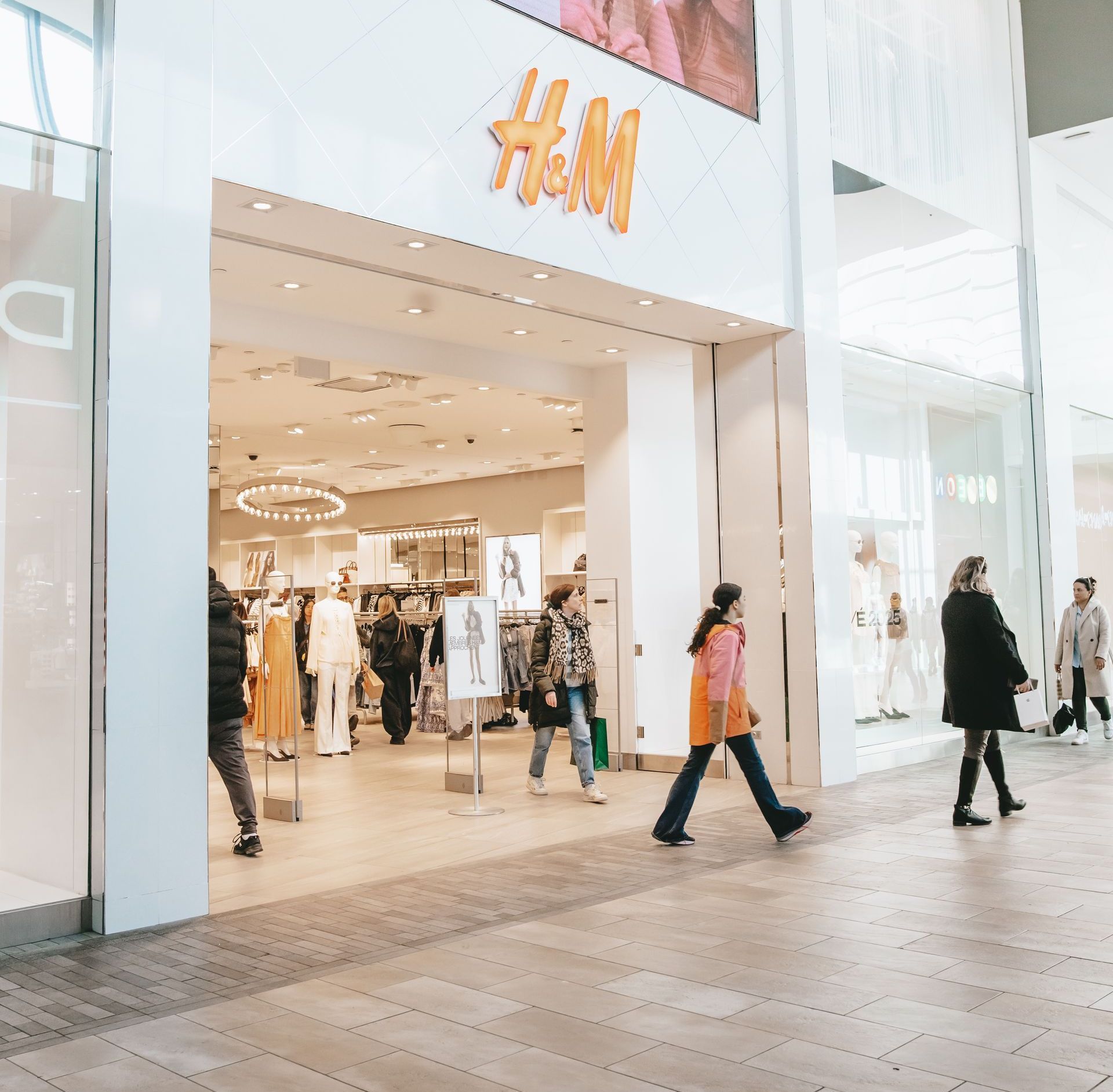 Un groupe de personnes marche devant le magasin Ah & M