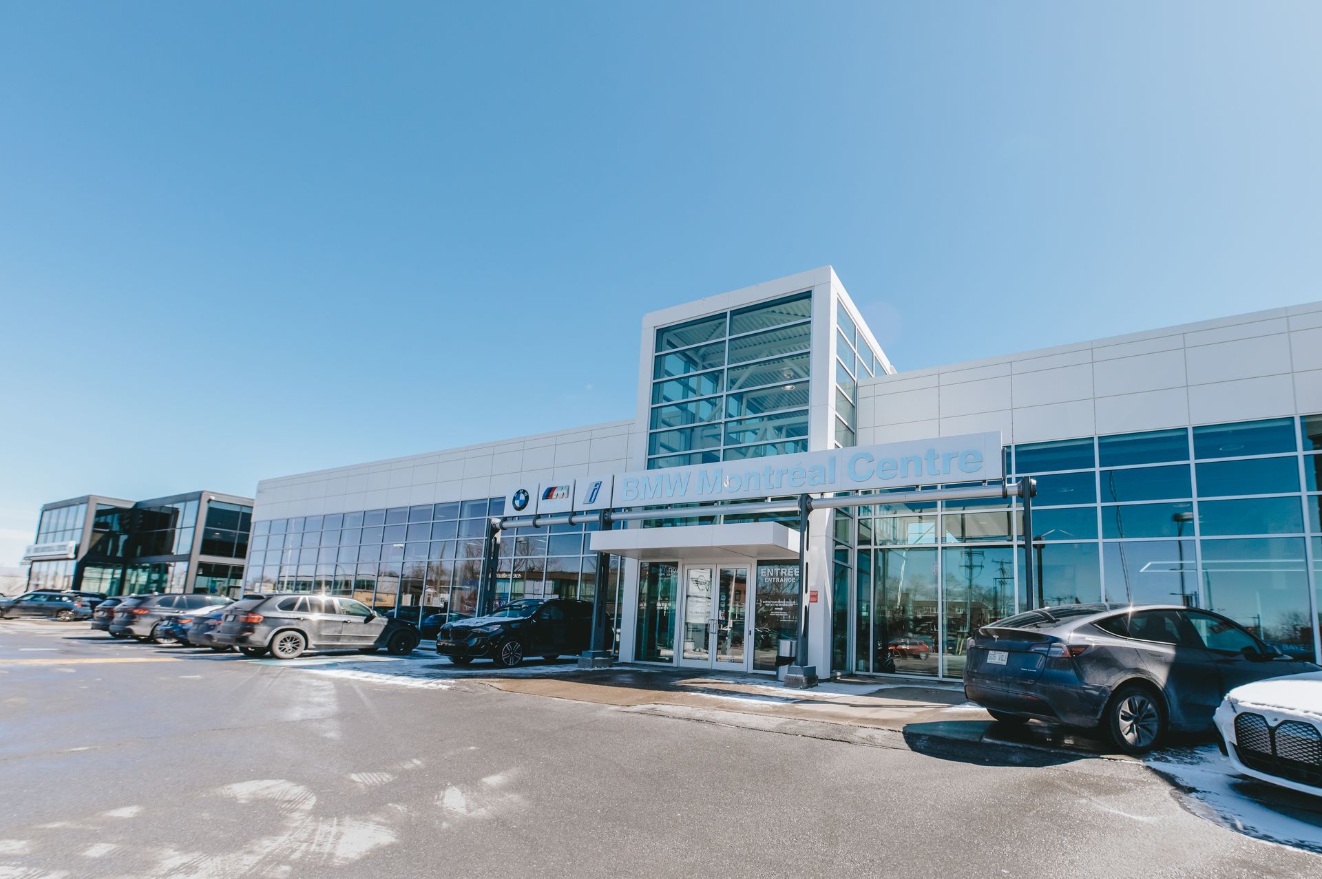 Une rangée de voitures est garée devant un grand bâtiment.