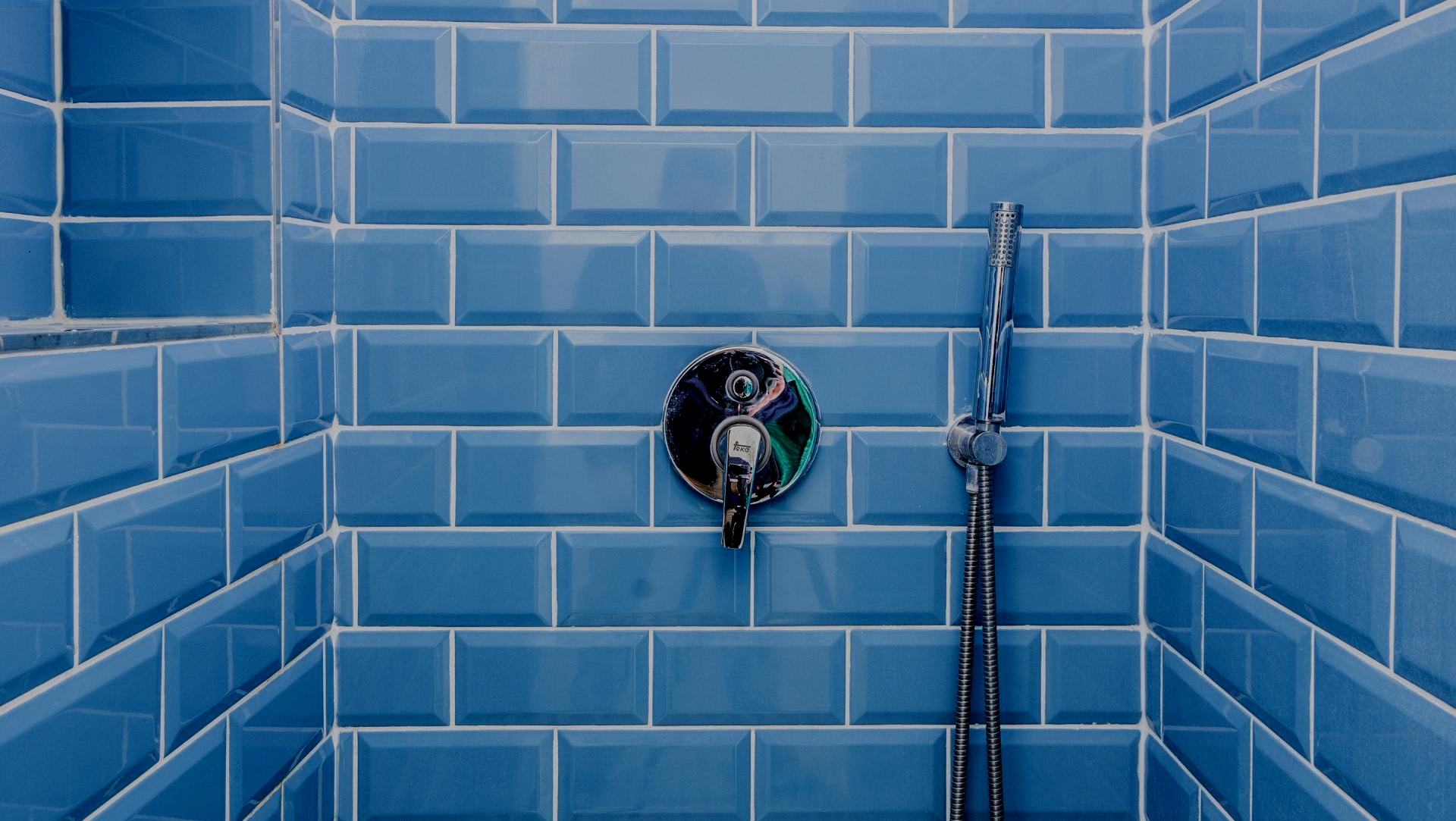 A shower stall with blue tiles and a shower head.